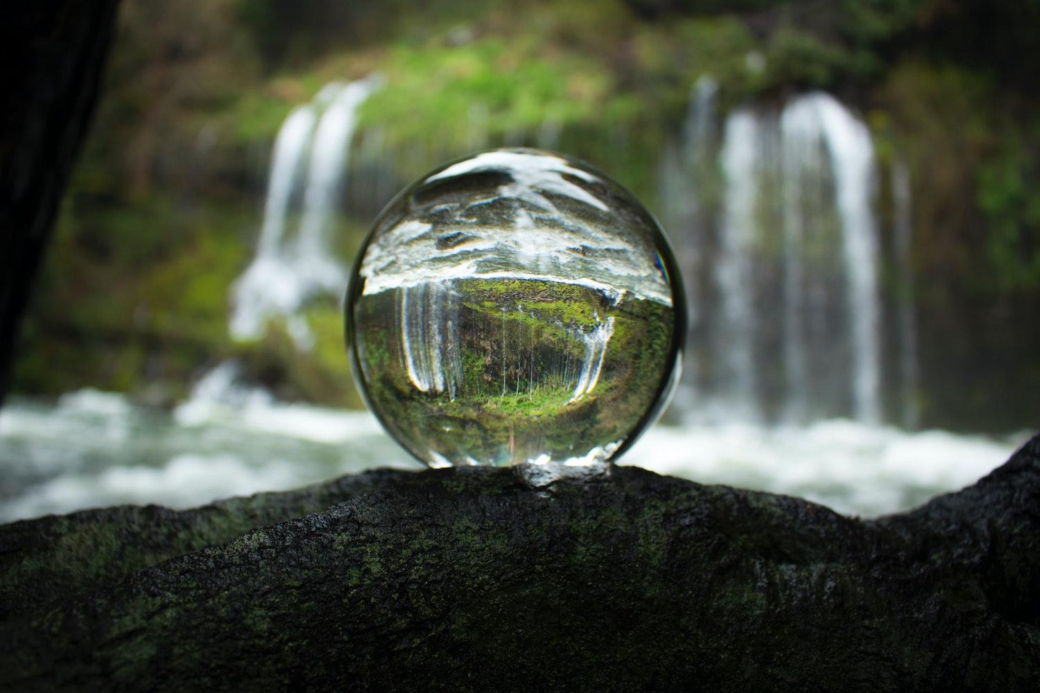Glass ball reflecting forest and waterfall - Water Stewardship - water stewards - sustainability