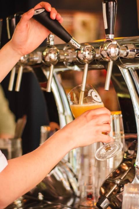 A bartender pouring a glass of beer. 