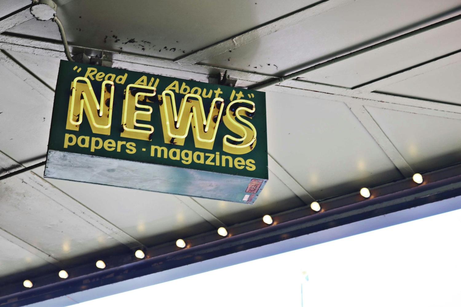 A sign reads "Read all about it. News. Papers. Magazines." 
