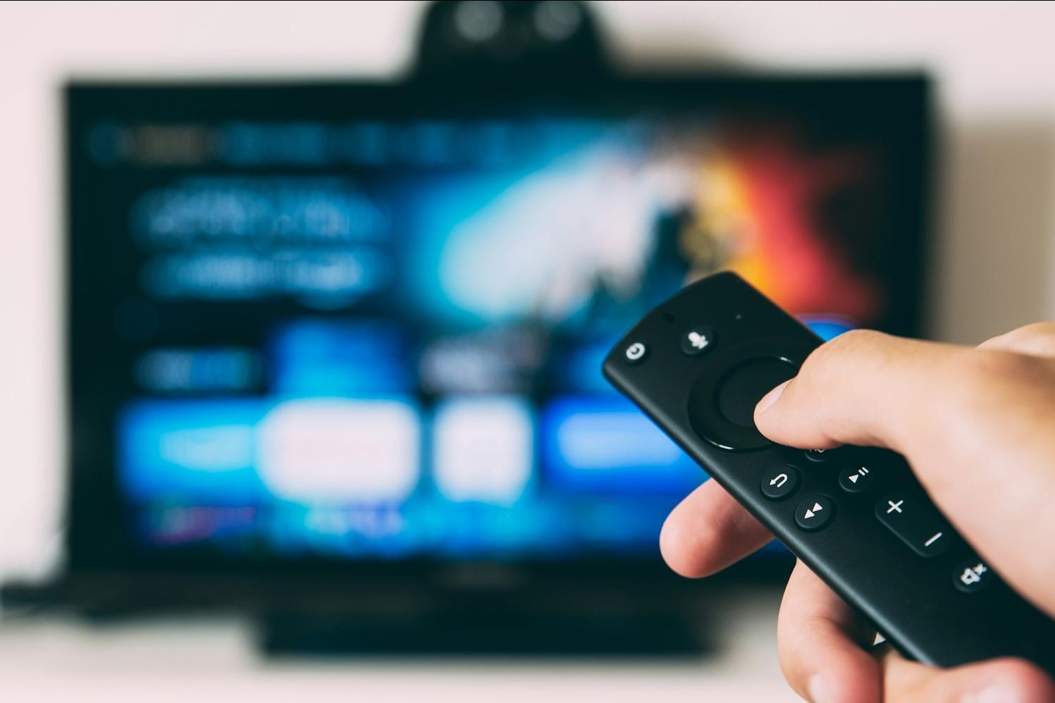 person watching the super bowl - television blurred out and hand with remote