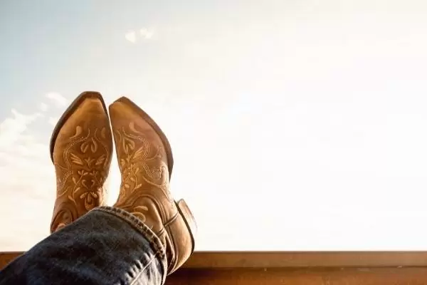 pair of slip on work boots worn under jeans on a sunny day